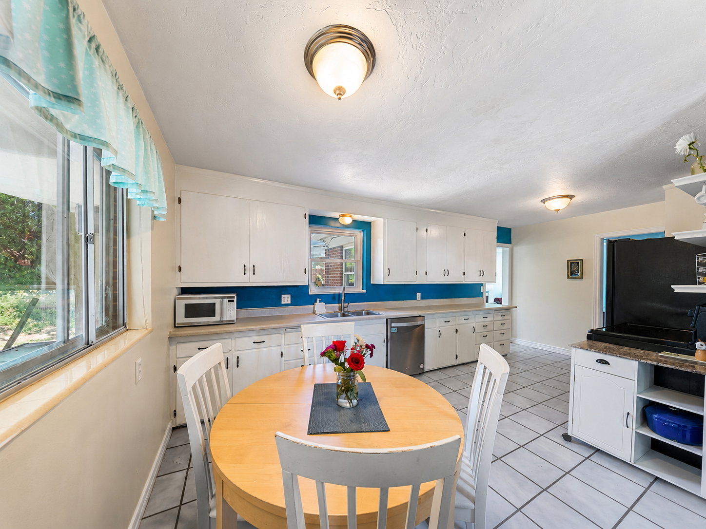 Well-appointed kitchen featuring white cabinetry, light countertops, and a stainless steel dishwasher