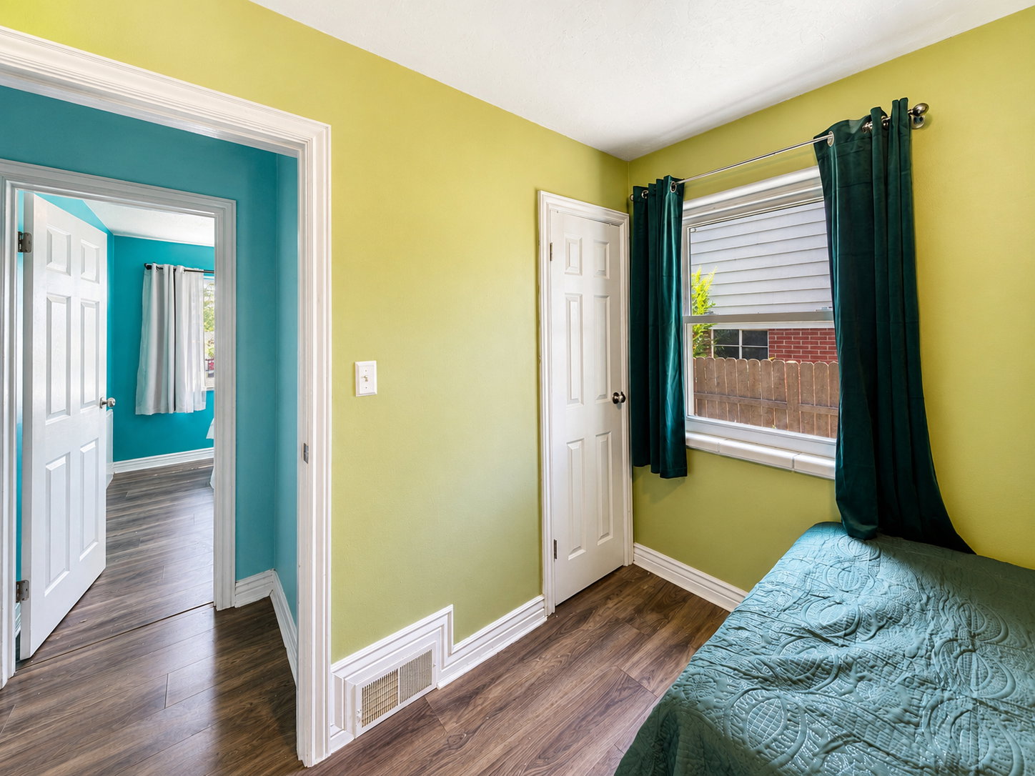 Bedroom featuring wood-finish flooring, a six-panel door, and a white window frame