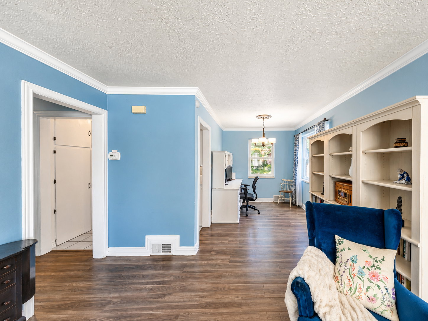 Spacious interior featuring wood-finish flooring, light blue walls, and white crown molding