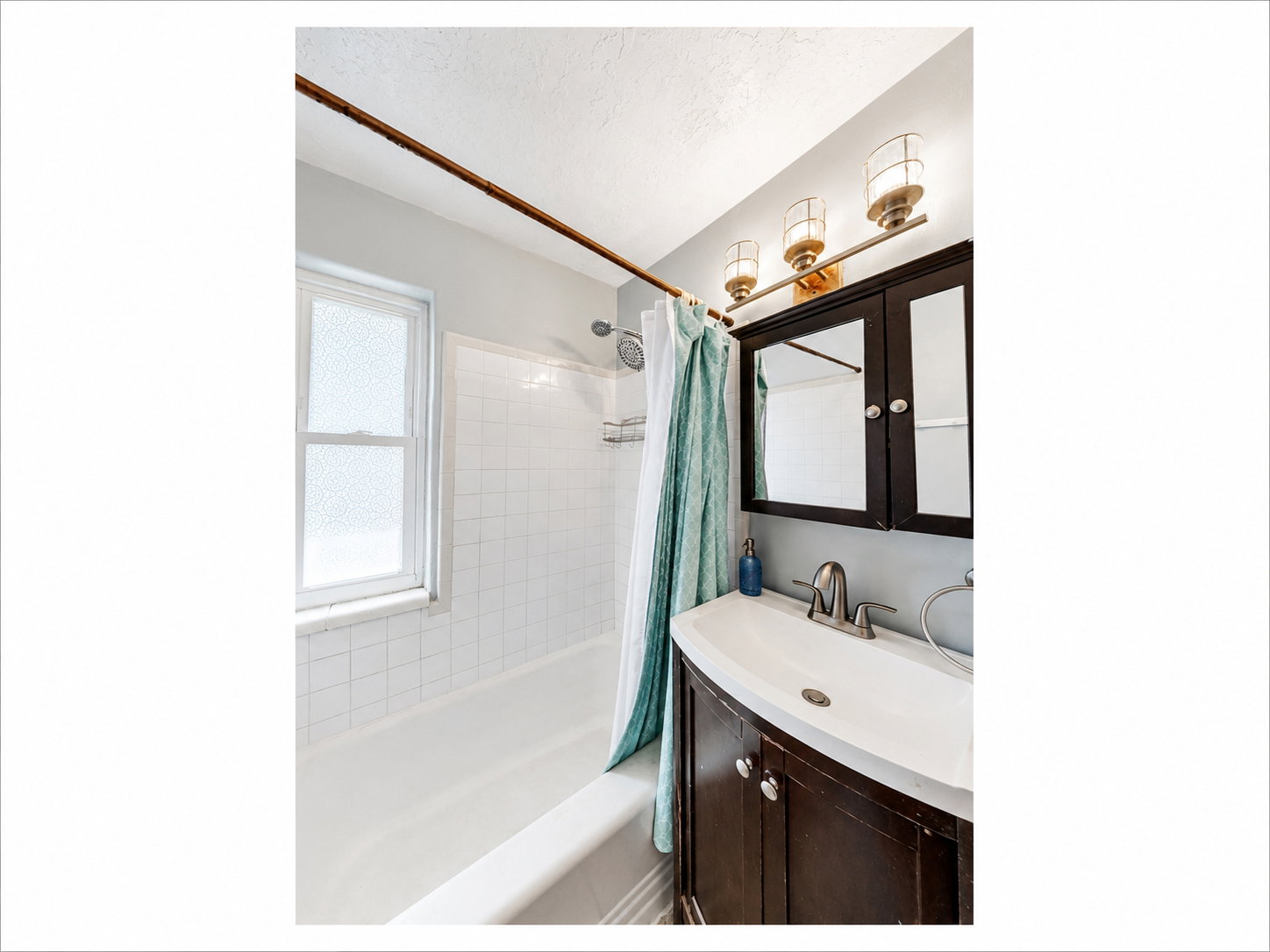 Bathroom featuring a dark wood vanity with an integrated sink, a matching medicine cabinet, and a three-light fixture