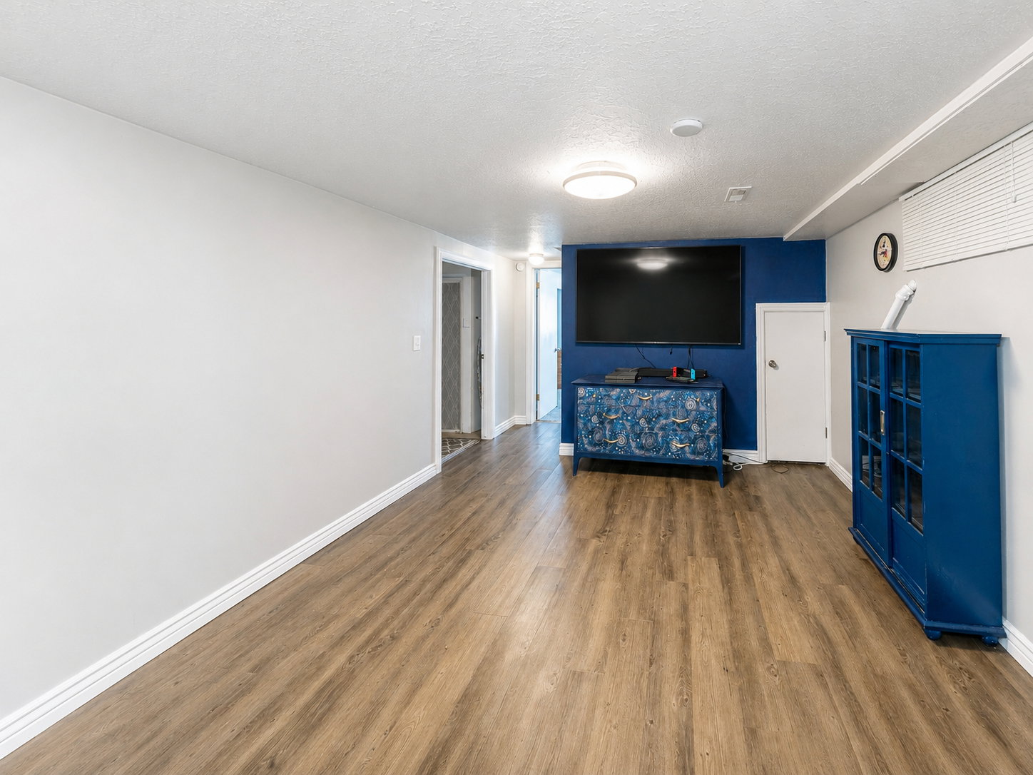 Spacious room featuring wood-finish flooring, light grey walls, and a recessed baseboard trim