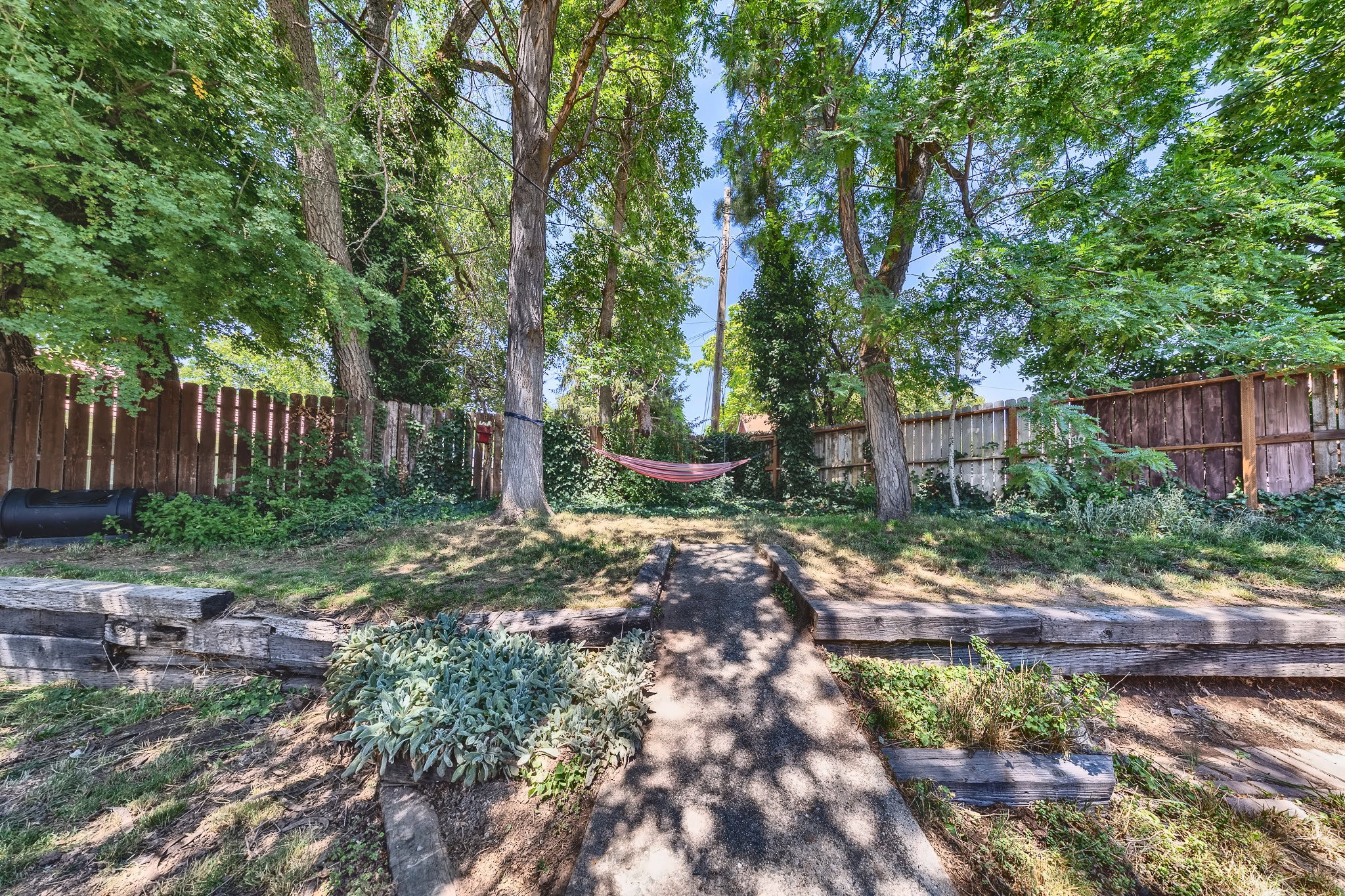Tiered backyard featuring mature trees, wood privacy fencing, and concrete steps